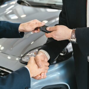 Close-up of a business handshake as car keys are handed over, symbolizing a new car purchase.